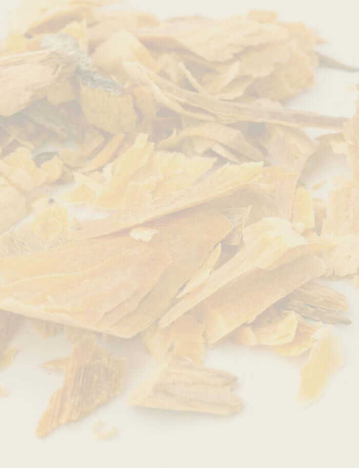 Close-up of golden cedarwood shavings, used for Cedarwood Essential Oil benefits.