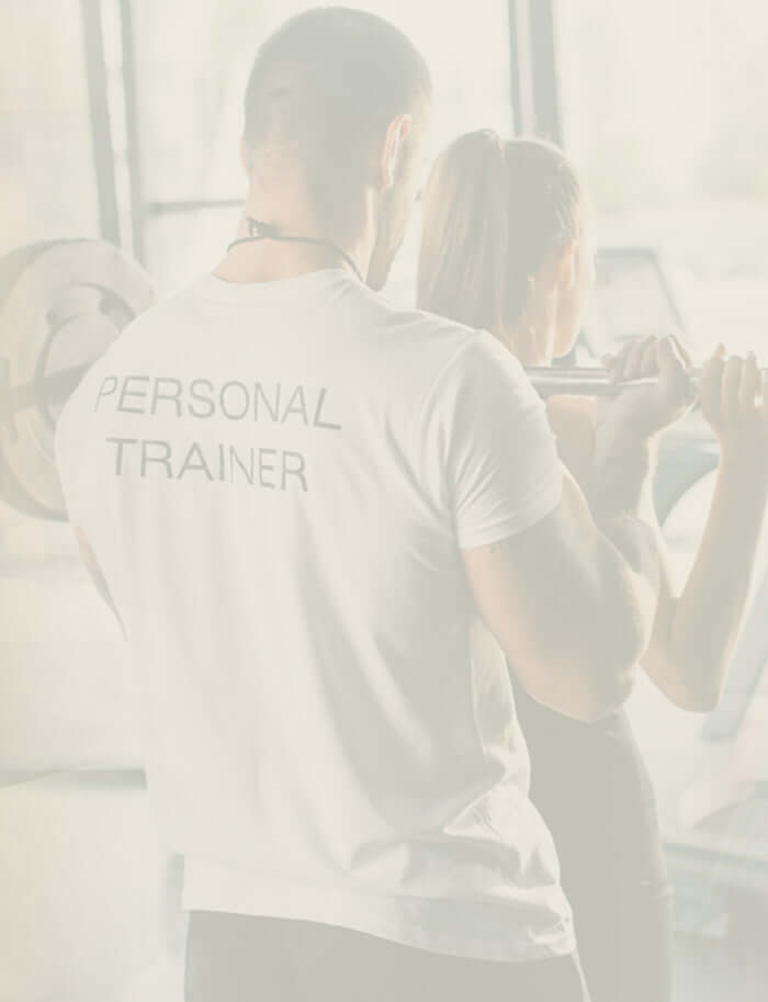 A fitness trainer guiding a client through resistance training at the gym.