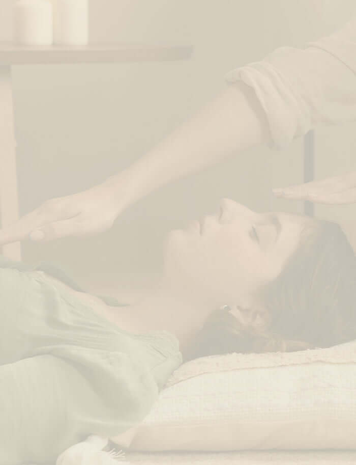 A woman receiving holistic therapy with energy healing and facial massage.