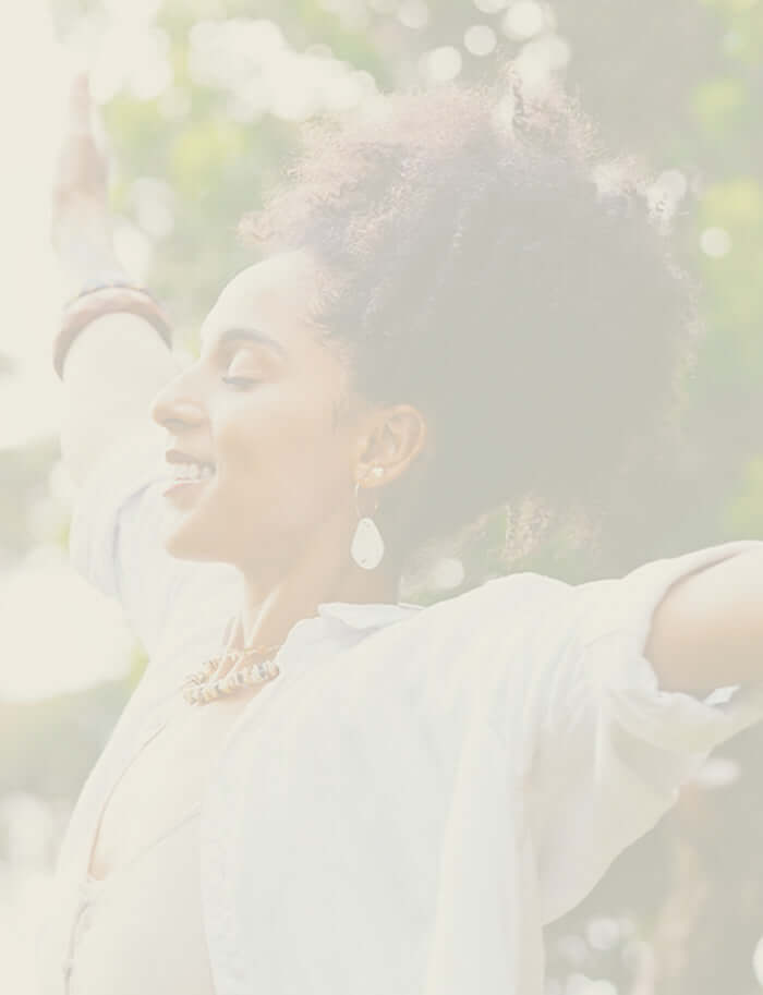 Joyful woman outdoors with open arms, representing wellbeing and inner peace.