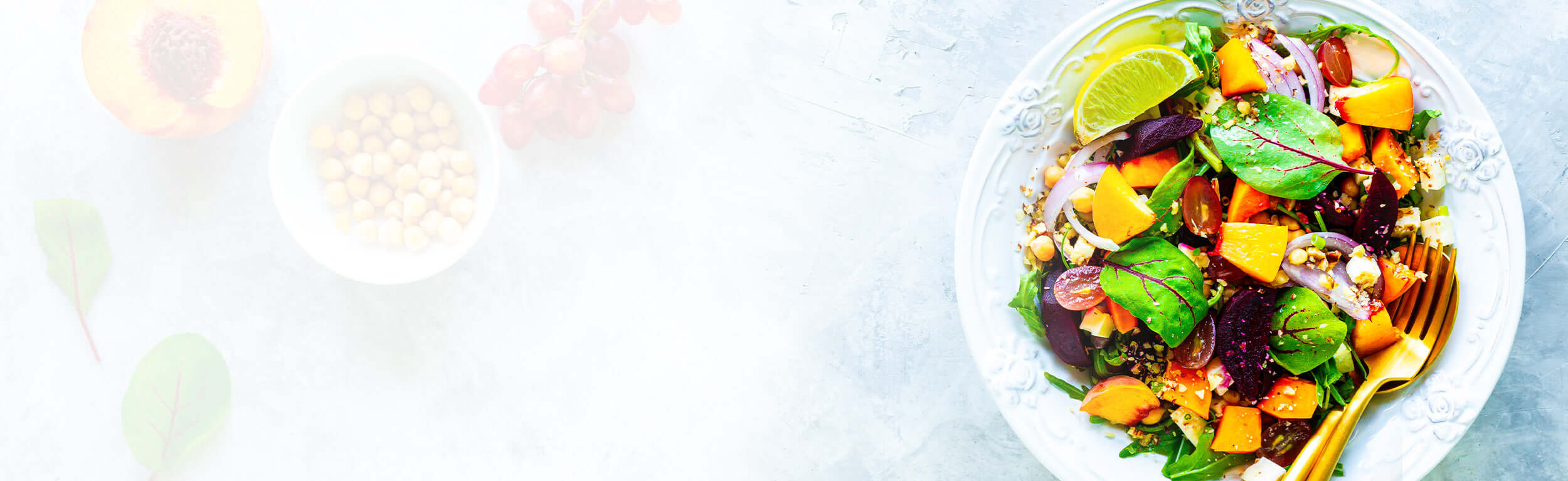 A healthy salad on a white plate with gold cutlery