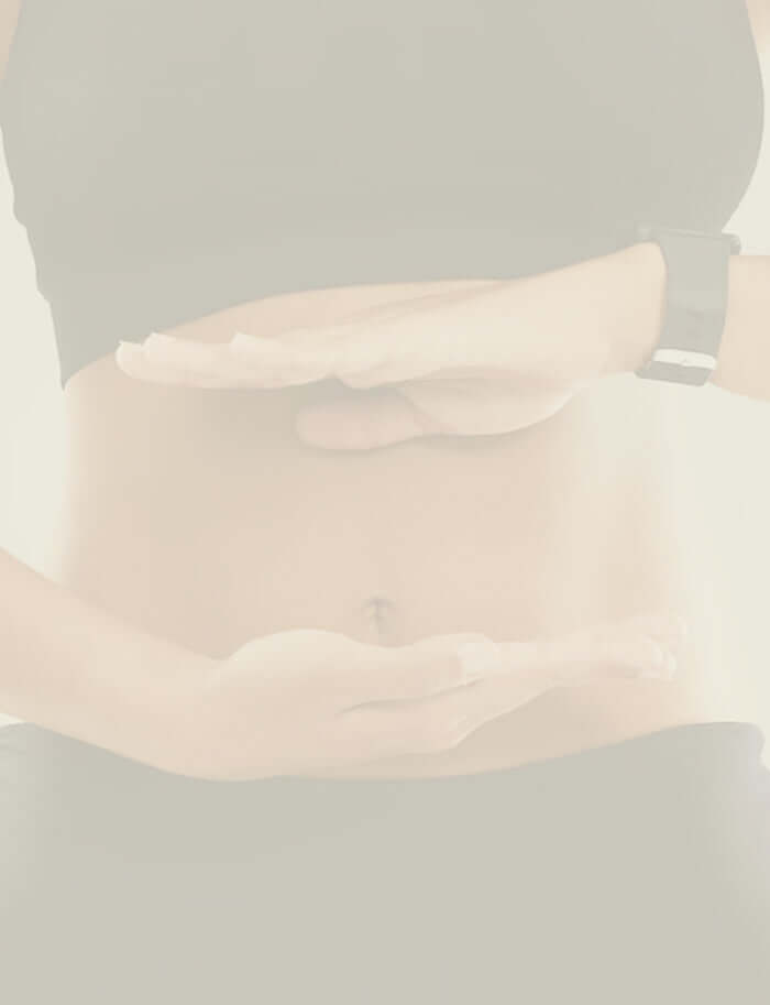 A woman in black work out clothes holding her hands horizontally against her stomach