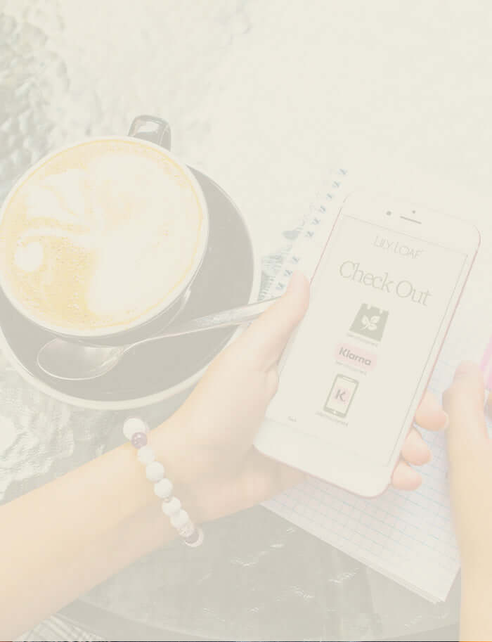 A person shopping on their phone whilst enjoying a cappuccino