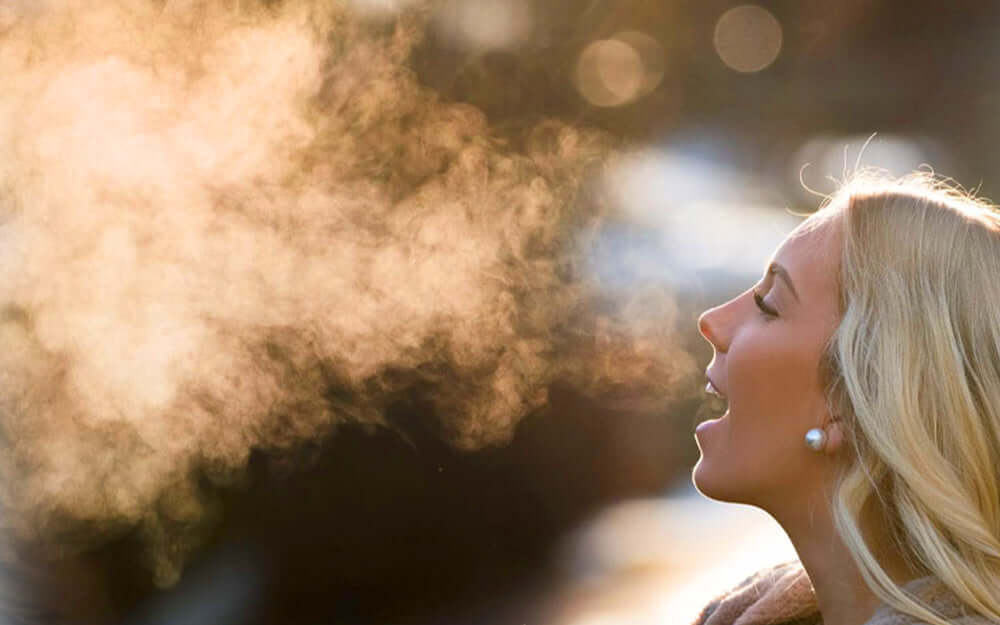 A woman breathing on a cold day showing breathe clouds