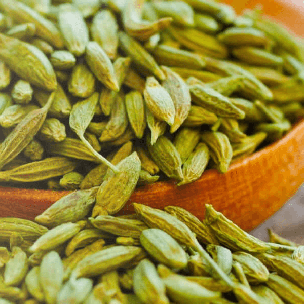 Close-up of dried fennel seeds in a wooden bowl with scattered seeds around