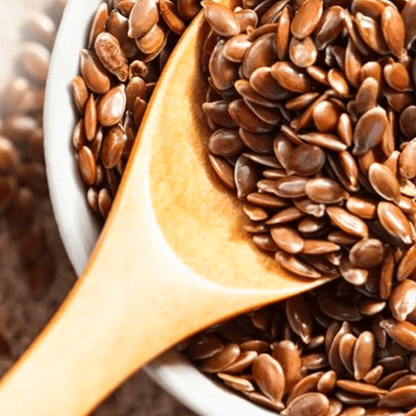 A wooden spoon in a bowl full of flax seeds