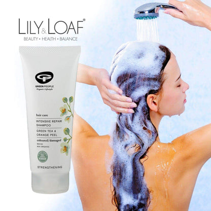 A woman shampooing her hair with Green People Intensive Repair Shampoo in the foreground